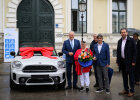 Innenminister Joachim Herrmann mit Gewinnern neben BMW Mini mit Schleife