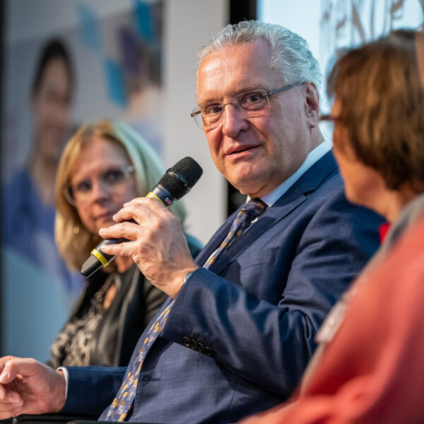 Herrmann mit Mikrofon bei Diskussion, neben ihm Teilnehmerinnen