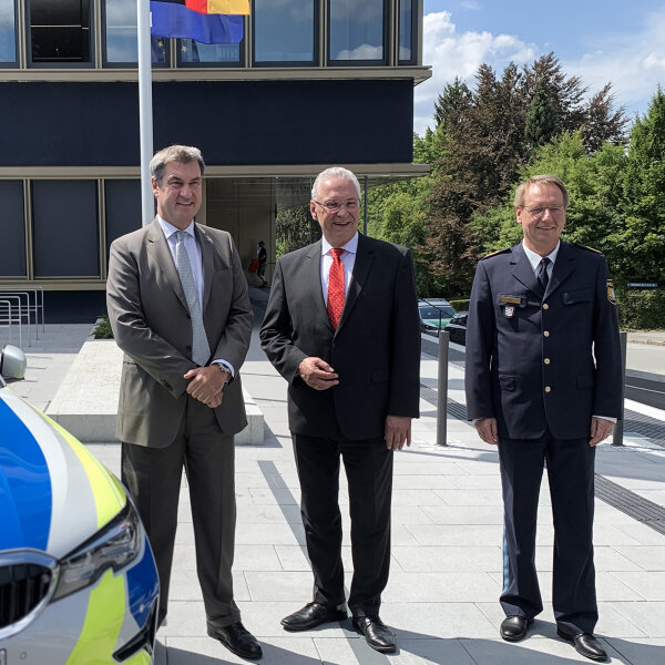 Ministerpräsident Dr. Markus Söder, Innenminister Joachim Herrmann und Polizeibeamter neben Polizeiauto vor Gebäude