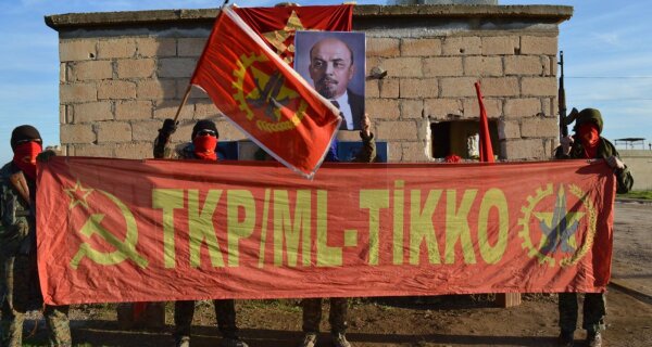 Das Bild zeigt Aktivisten der TKP/ML-TIKKO vor einer Gebäudewand mit Bannern und Fahnen und einem Lenin-Portrait