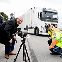 Herrmann und Polizist mit Kontrollgerät, im Hintergrund ein LKW